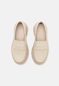 Beige slip-on cipők sima bőr felsőrésszel, díszes csillagmintákkal a pánton, és texturált gumitalp a jó tapadás érdekében.