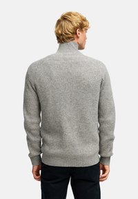 Szary sweter o prążkowanym dzianinie z wysokim kołnierzem i dopasowanymi mankietami. Posiada teksturowany materiał i lekko luźny krój u dołu.