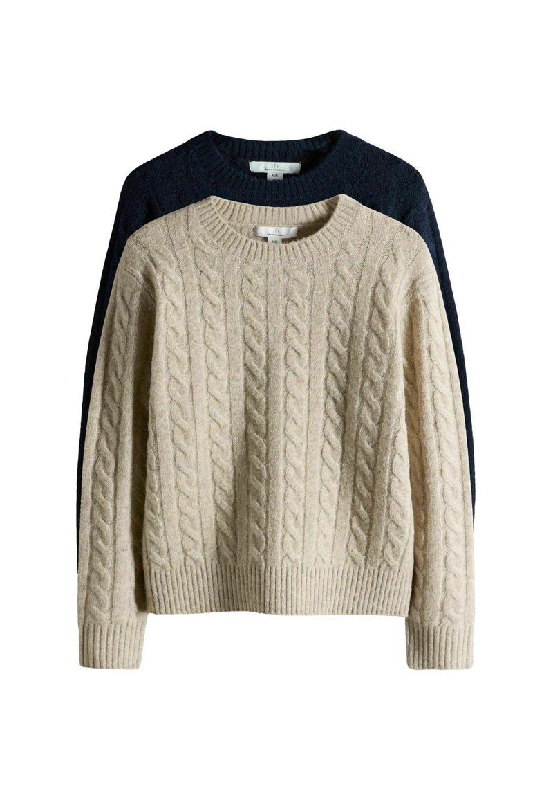 Light beige cable-knit sweater in front, dark blue behind. Both have a ribbed crew neck and cuffs, featuring textured, raised patterns.