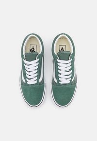 Grønn semsket sneakers med hvite lisser, hvit sidestripe og svart gummisåle. Rund tå og sømdetaljer på overdelen.