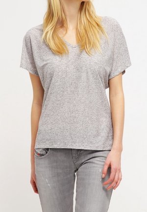 T-shirt grigio a maniche corte con scollo a V, caratterizzato da un motivo a righe testurizzato. Abbinato a jeans chiari strappati di colore grigio.