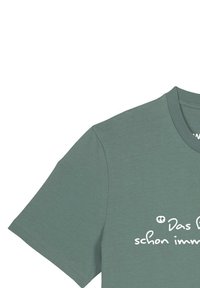 T-shirt vert à manches courtes avec un col rond et un imprimé en texte blanc. Le tissu semble lisse avec une coupe décontractée et relaxée.