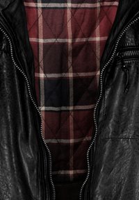 Zwarte leren jas met een ritsluiting, voorzien van een rood en marineblauw geruit gevoerd interieur en een gestructureerde buitenkant.