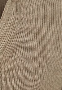 Beige gebreide stof met een geribbelde textuur en een gladde afwerking, met uniforme lijnen en een zachte uitstraling.