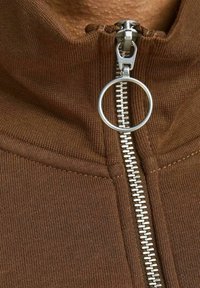 Chaqueta marrón con cremallera metálica y tirador circular, textura acanalada y diseño de cuello alto.