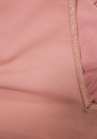 Blusa en color rubor con tela de seda y una textura suave, acentuada por un delicado y brillante borde en el escote.