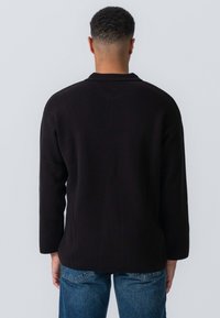 Sort, langærmet trøje med en afslappet pasform. Fremstillet af blødt stof, den har et enkelt design og en rund halsudskæring. Bæres med blå jeans.