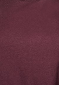 Burgundijas kokvilnas audums ar gludu tekstūru, ar apaļu kakla izgriezumu un bez redzamām rakstu vai akcentu detaļām.