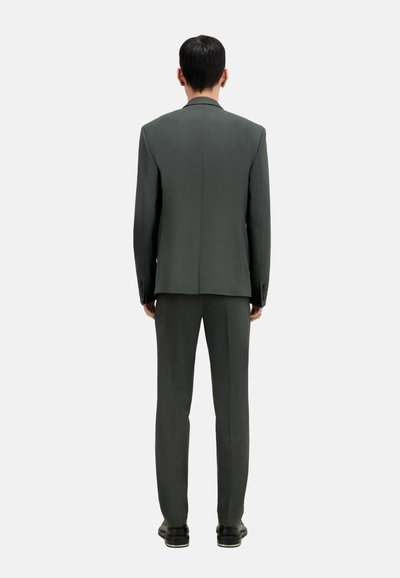 Abito grigio scuro con un blazer strutturato e pantaloni abbinati. Il materiale appare liscio con texture minima. Nessun motivo o accessorio visibile.