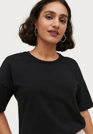 Sort bomulds t-shirt med en klassisk rund halsudskæring og korte ærmer, der har en afslappet pasform og en glat tekstur.