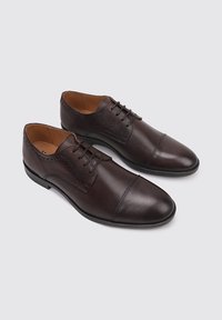Zapatos de vestir de cuero marrón con un acabado suave, diseño de cordones, puntera redonda, detalles perforados y forro interior de color marrón claro.