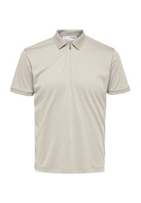 Polo beige clair en tissu lisse, doté d'un col à fermeture éclair partielle et d'un col texturé avec des manches courtes. Aucun motif ou accent notable.