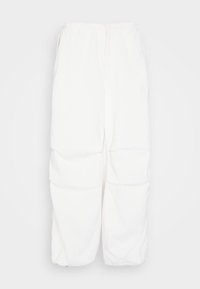 Pantalones blancos, holgados, con una tela texturizada, que presentan una cintura con cordón y recogidos a la altura de la rodilla para dar forma. Sin bolsillos visibles.