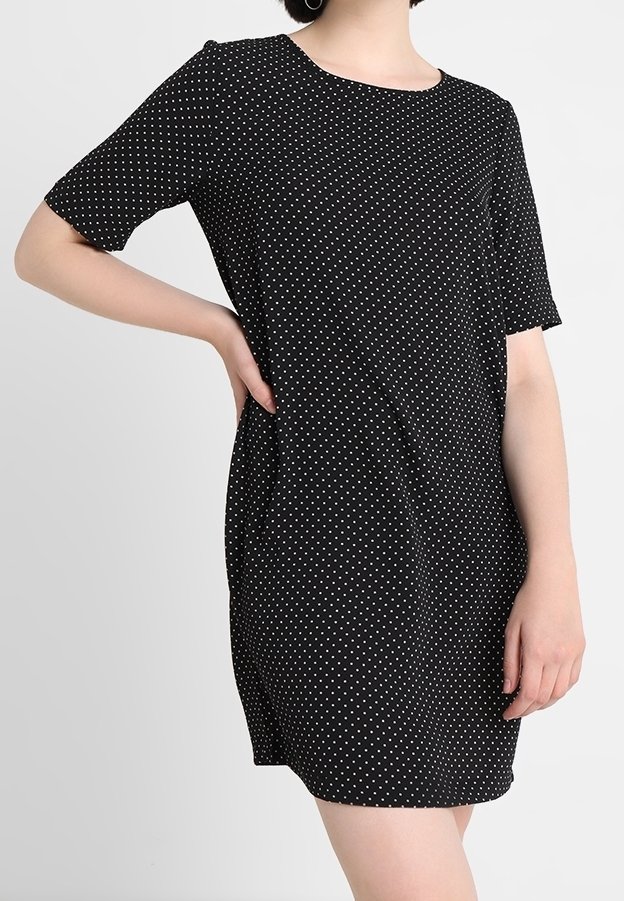 Robe noire à manches courtes avec des pois blancs, décolleté rond et coupe décontractée. Tissu doux avec une texture lisse et sans fermetures visibles.