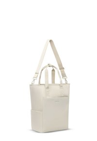 Sac fourre-tout couleur crème avec deux poignées courtes, une longue bandoulière réglable et une poche avant, sur fond blanc.