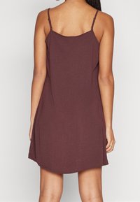 Burgundy ärmlös klänning med tunna band, mjukt tyg, avslappnad passform och en lätt utvidgad nederkant. Enkel design och mångsidig.