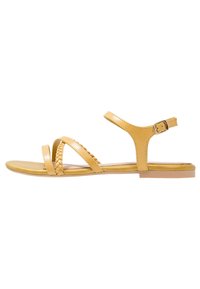 Sandales en cuir jaune avec des brides tressées, une sangle à la cheville avec fermeture à boucle et une semelle plate. Design minimaliste avec bout ouvert.