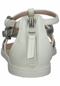 Sandal in pelle bianca con cintura argentata, chiusura con zip sul retro e ricami intricati. Presenta un design a intaglio e accenti testurizzati.