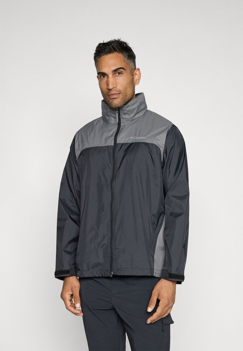 Chaqueta de cremallera negra y gris con alto cuello, fabricada con un material ligero y resistente al agua, y con un panel de contraste en los hombros.