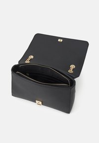 Černá kožená kabelka s hladkou texturou, zlatým kováním a zipem uvnitř. Víko se otevírá a odhaluje prostorný oddíl.