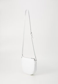 Bela torbica preko ramena z okroglo obliko, gladko teksturo, nastavljivim trakom in srebrnimi detajli z zadrgo.