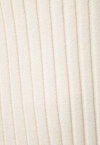 Textured fabric in soft cream color, featuring vertical ribbing patterns. Material appears plush with a slight sheen, suggesting comfort.