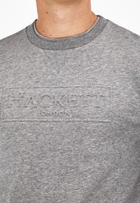 Sudadera gris con cuello redondo y detalle del logo texturizado "HACKETT LONDON" en el frente, confeccionada con una suave tela de peso medio.