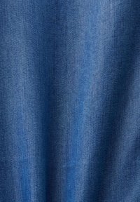 Tissu en denim bleu avec une texture visible et des lignes de couture verticales, présentant de légères plis et des variations d'ombrage.