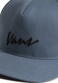 Blå stofkasket med et struktureret design. Har et sort broderet "Vans" logo foran og et tekstureret, ribbet materiale.
