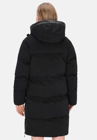 Zwarte pufferjas met capuchon, voorzien van een gestikte ontwerp, met ritszakken aan de zijkant en een middellange snit. Matte afwerking met subtiele textuur.