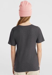 Grijze T-shirt met korte mouwen en een ronde hals. Zachte textuur. Een roze beanie op het hoofd voegt kleurcontrast toe. Eenvoudig en casual ontwerp.
