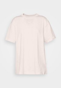 Světle růžové bavlněné tričko s volným střihem, krátkými rukávy a kulatým výstřihem. Na hrudi má malé bílé logo Nike.