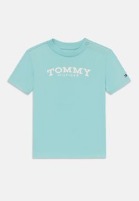 Svetlo modré tričko s krátkym rukávom vyrobené z bavlny, s potlačou loga "TOMMY HILFIGER" v bielej farbe na prednej strane a malým logom na rukáve.