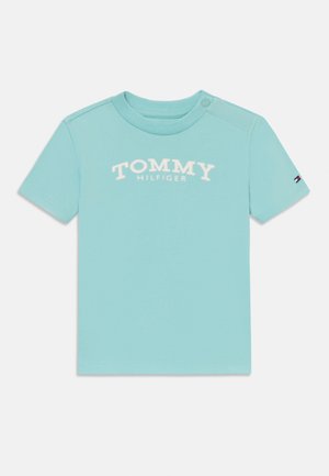 Hellesblaues T-Shirt mit kurzen Ärmeln aus Baumwolle, mit aufgedrucktem "TOMMY HILFIGER"-Logo in Weiß auf der Vorderseite und kleinem Logo- Akzent auf dem Ärmel.