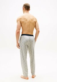 Pantalones de pijama grises con un patrón, con una cintura elástica negra, que cuentan con un corte holgado y sutiles diseños geométricos en toda la tela.