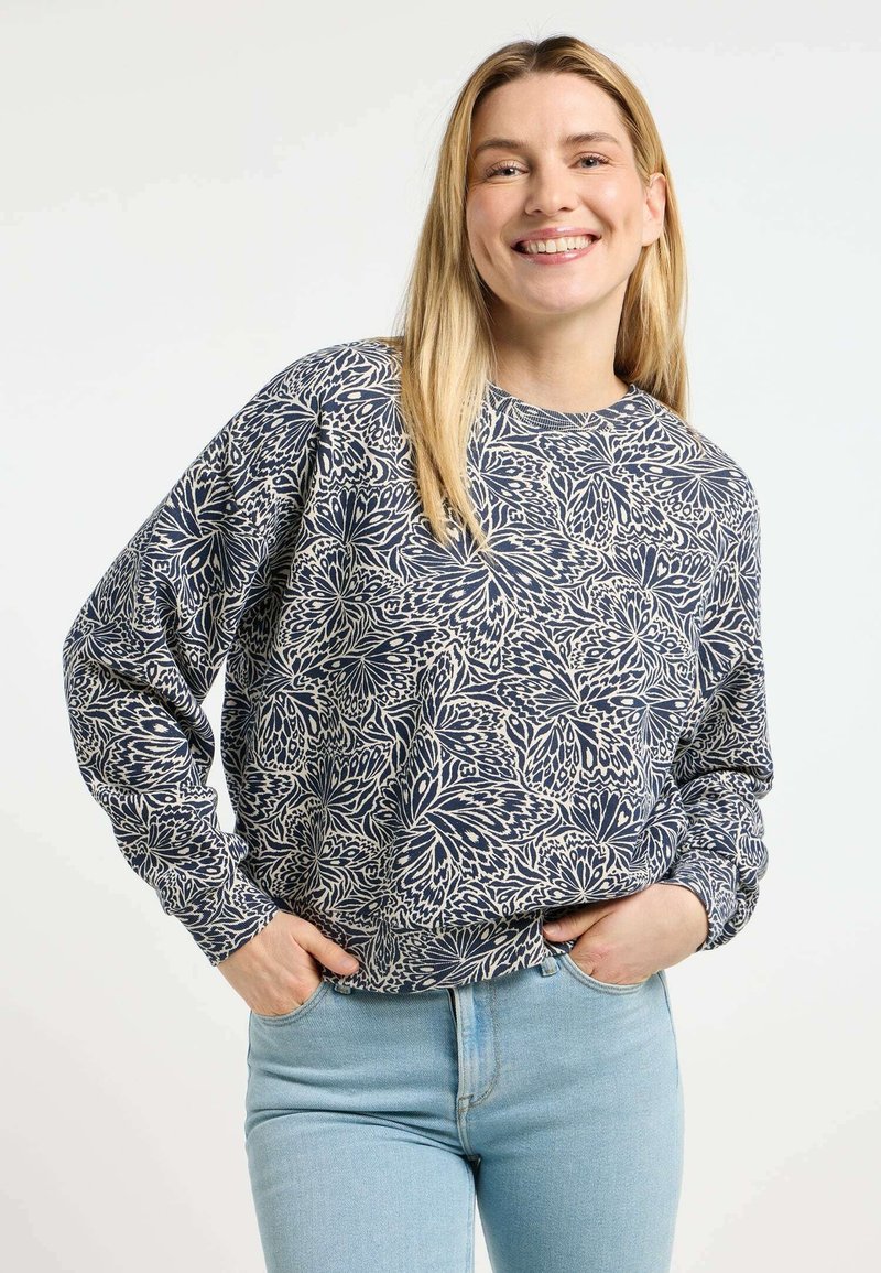 Felpa navy con motivo floreale crema, scollatura rotonda e maniche lunghe, abbinata a jeans blu chiaro. Tessuto morbido.