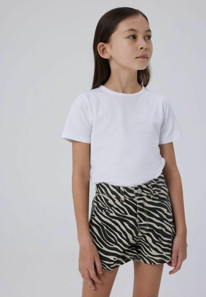 Vit t-shirt med kort ärm, kombinerad med svart och beige randyshorts med hög midja, som har framfickor och knäppning.