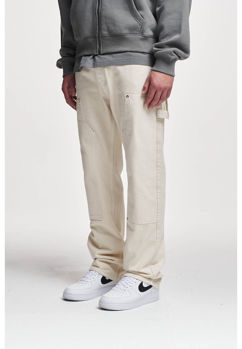 Beige cargobroeken van katoen, met meerdere zakken, knoopaccenten en een relaxte pasvorm. Gecombineerd met witte sneakers.