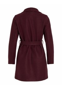 Vīna sarkanā mētelis ar garām piedurknēm, jostu viduklī un klasisku apkakli. Izgatavots no teksturēta, siltā auduma. Nav redzamu aizdaru.