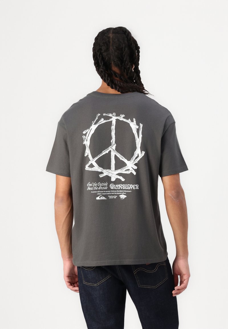 Graues Baumwoll-T-Shirt mit einem weißen Friedenssymbol-Graphic auf der Rückseite, oberhalb von Text und Branding, mit kurzen Ärmeln und lockerem Schnitt.