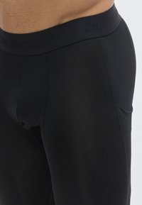 Μαύρα αθλητικά σορτς από ελαστικό υλικό, με στενή μέση που φέρει ανάγλυφο λογότυπο "JORDAN" και λεπτομέρεια πλευρικής τσέπης.