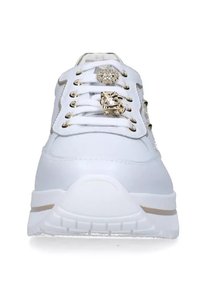 Sneaker bianco con materiali in mesh e sintetici, occhielli tono oro, dettagli decorativi e suola testurizzata. La vista frontale mette in mostra i lacci e il logo.
