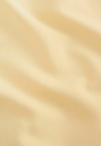 Tissu doux de couleur jaune pâle avec une texture lisse et un subtil nervurage, présentant des plis et des courbes délicats.