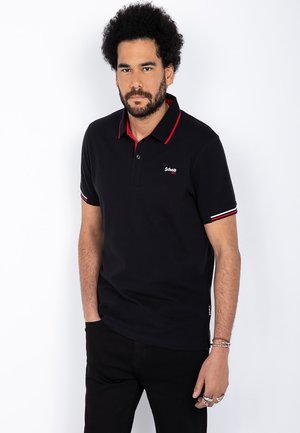 Polo negro con acentos rojos en el cuello y las mangas, con una tapeta de tres botones y un logo bordado en el pecho. Material de algodón.