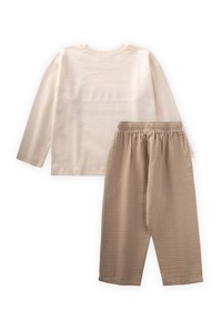 Top beige a maniche lunghe con scollo a costine abbinato a pantaloni beige chiaro testurizzati con una fascia elastica in vita. Materiale morbido e casual.