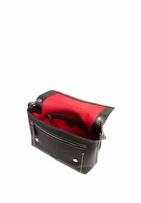 Sac à main en cuir noir avec quincaillerie en argent, intérieur rouge, poche zippée et coutures blanches contrastées. Design ouvert avec des anses en chaîne.