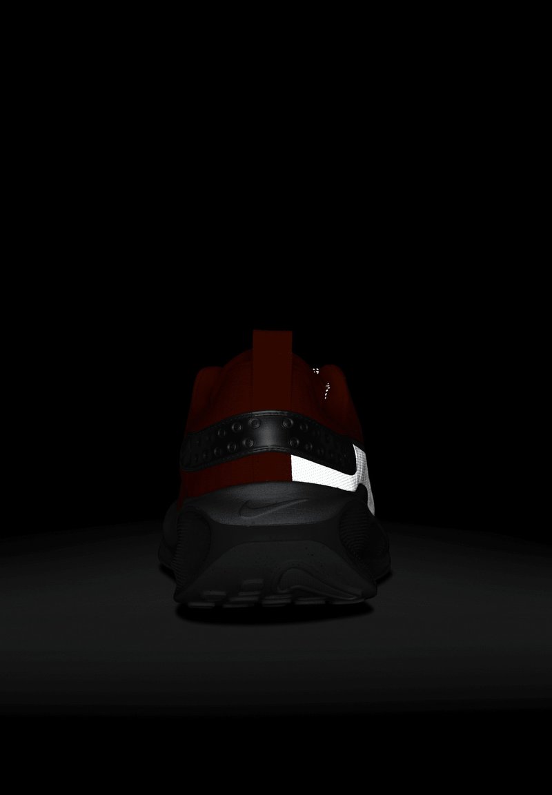 Czerwony but sportowy z czarną podeszwą, z odblaskowym białym akcentem i teksturowanym czarnym pasem na śródpodeszwie, z pętlą z tyłu.