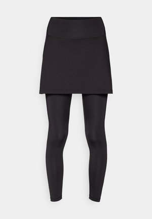 Černá atletická sukně přes černé legíny, vyrobená z elastického materiálu. Sukně má široký pas a hladký povrch.