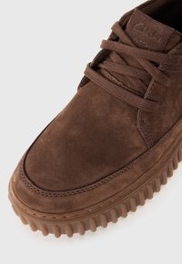 Baskets en daim marron avec un bout rond, une tige texturée et une semelle en caoutchouc avec des détails rainurés, ainsi que des lacets assortis marron.