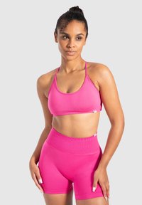 Roze sportbeha en high-waisted shorts gemaakt van rekbare stof. Beide hebben een gladde textuur en een minimalistisch ontwerp met dunne bandjes.